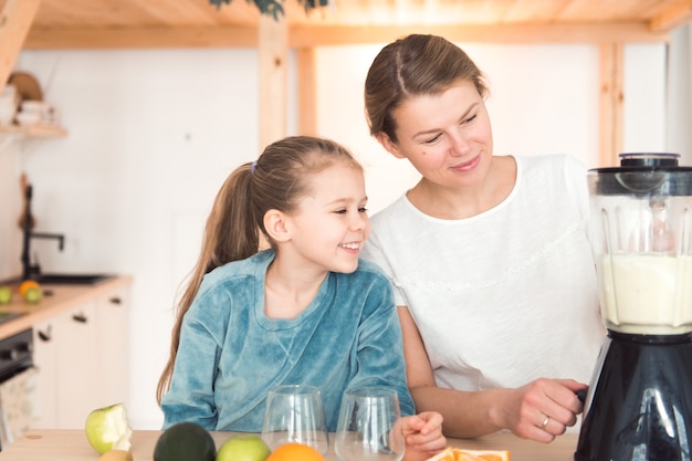 Girl make smoothie in blender with mother