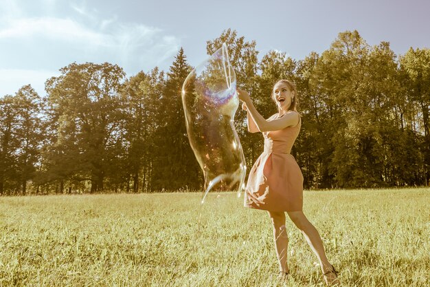 A girl makes big soap bubbles in the park