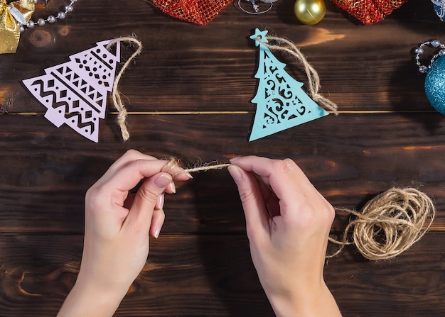 Girl makes Christmas decorations on a dark wooden table.