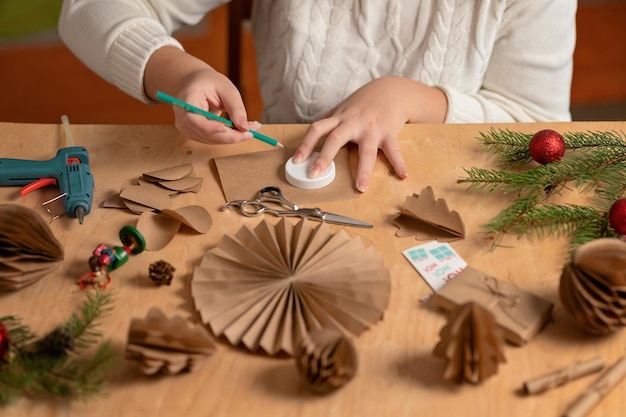 girl makes Christmas tree decorations out of paper with her own hands step 1