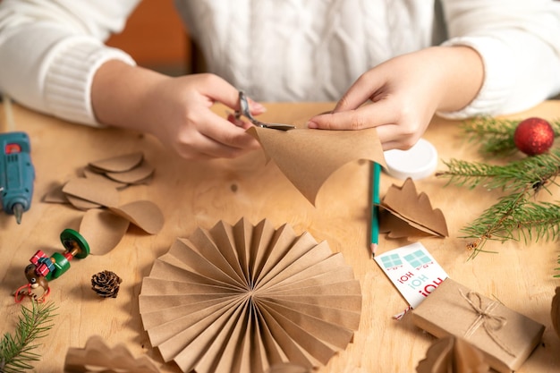 Photo girl makes christmas tree decorations out of paper with her own hands step 2