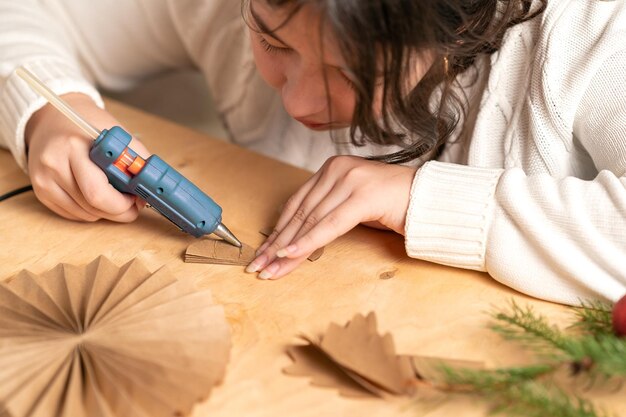 Photo girl makes christmas tree decorations out of paper with her own hands step 3