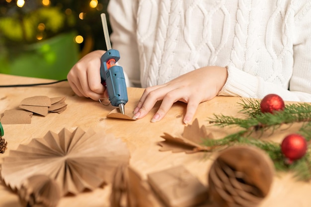 girl makes Christmas tree decorations out of paper with her own hands