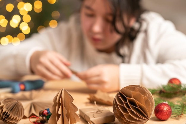 girl makes Christmas tree decorations out of paper with her own hands.