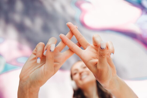 Foto la ragazza fa un hashtag con le mani una giovane donna che indossa le cuffie mostra un hashtag sullo sfondo della strada e dei graffiti