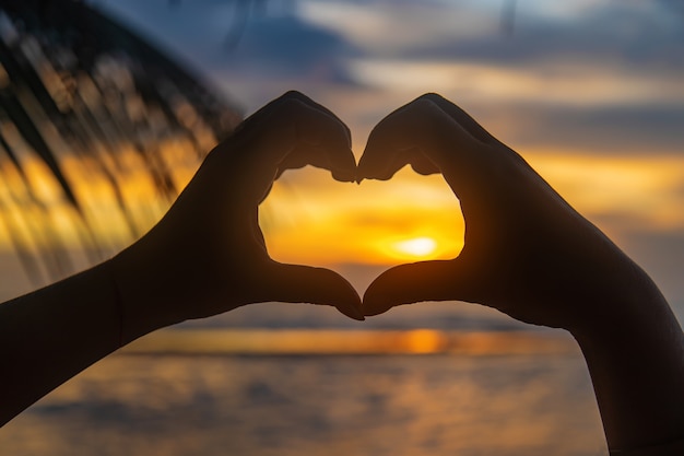 Girl makes heart hands at sunset. Sri Lanka.