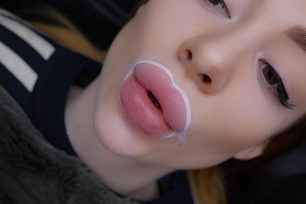 Girl makes a kiss with her lips before the procedure of permanent lip makeup