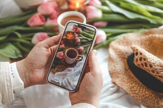 Photo girl makes a photo a cup of tea and flowers