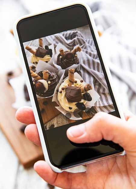 Girl makes a photo of cupcakes on a smartphone