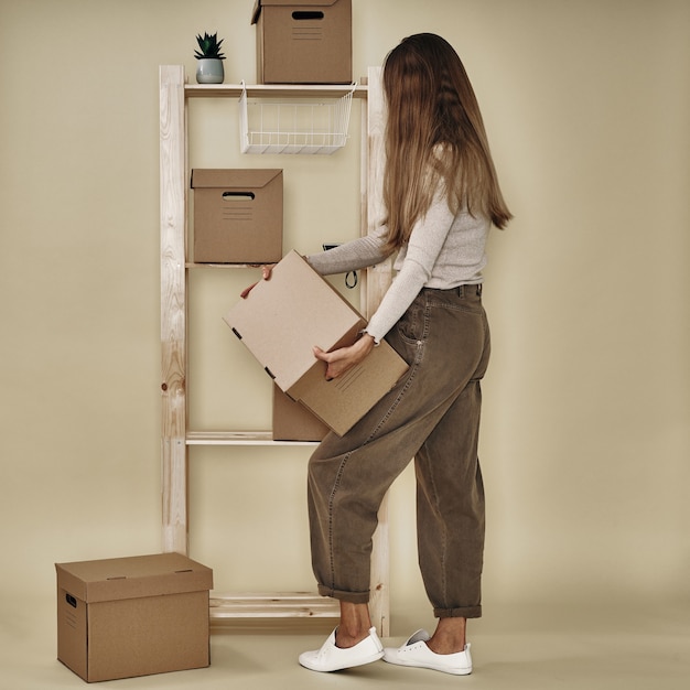 The girl makes up paper boxes on a wooden rack. Eco-friendly storage and packaging.