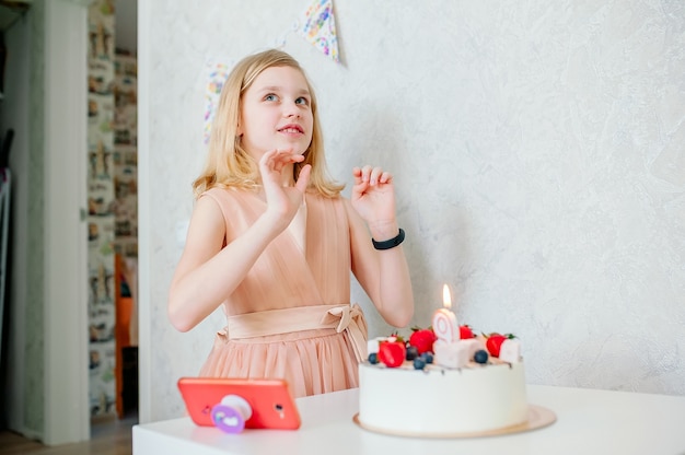 girl makes a wish, there is a cake on the table