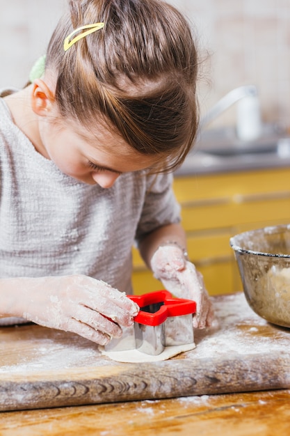 Ragazza che produce i biscotti del ritaglio