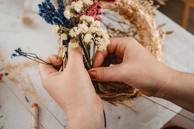 Foto ragazza che fa una ghirlanda floreale per la porta usando fiori secchi colorati d'estate e piante per la decorazione dei fiori d'autunno