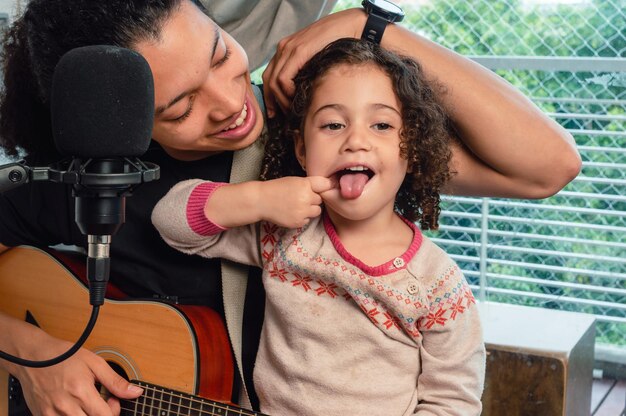 girl making funny face sticking out tongue interrupts her father during a music rehearsal