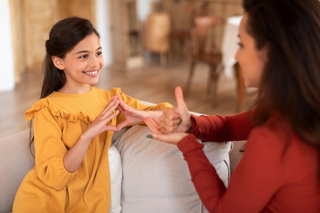 Girl making hand gesture using sign language with tutor indoor