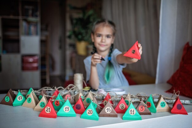 Girl making handmade advent Christmas calendar with color paper triangles