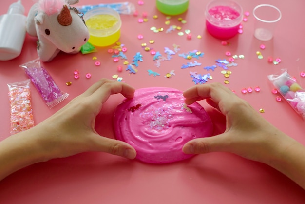 A girl making slime herself. child making slime on pink background.