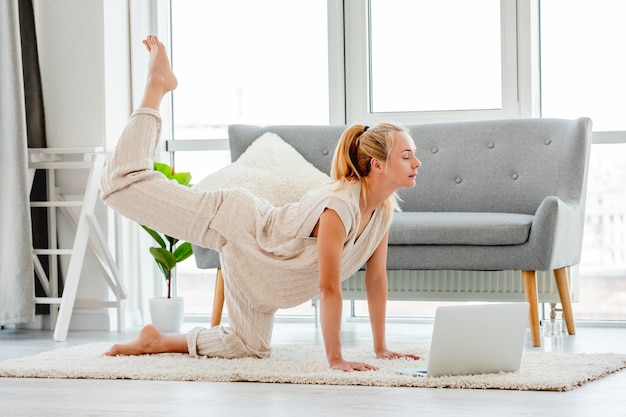 Girl making yoga online with laptop in sunny day