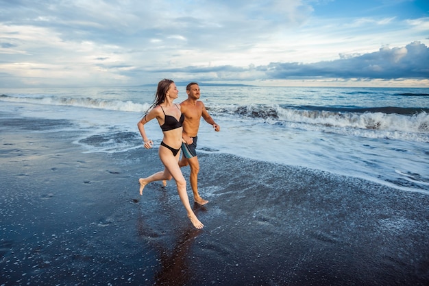 Girl and man on the beach running