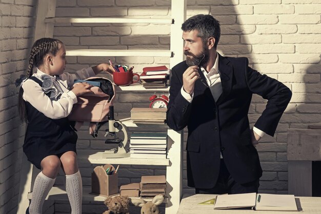 Photo girl and man near bookshelf with school supplies