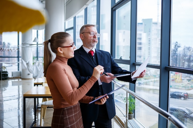 Girl manager in her own office tells a successful new business
plan for economic development to her teacher mentor boss. holds a
folder with important documents in his hands.