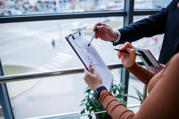 Girl manager in her own office tells a successful new business
plan for economic development to her teacher mentor boss. holds a
folder with important documents in his hands.