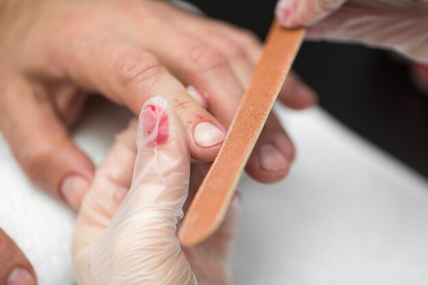 Girl manicurist doing manicure for man in beauty salon