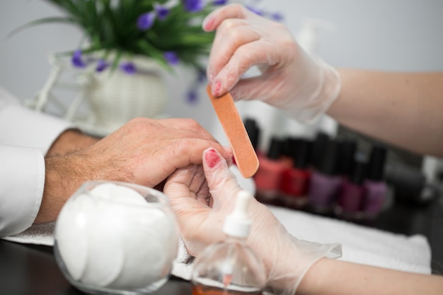 Girl manicurist doing manicure for man in beauty salon