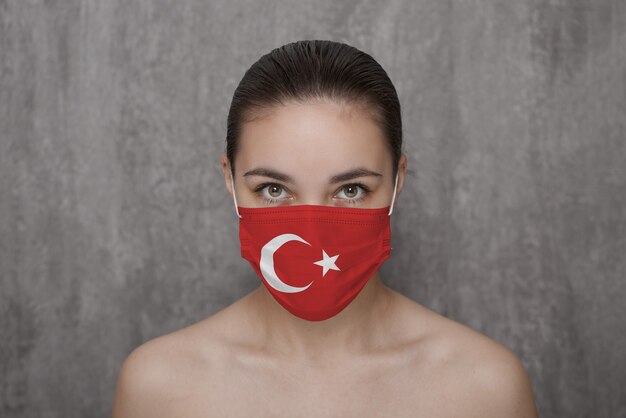 A girl in a mask on her face with a Turkish flag