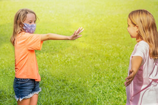 girl in the mask shows a stop for girl without a mask. social distancing.