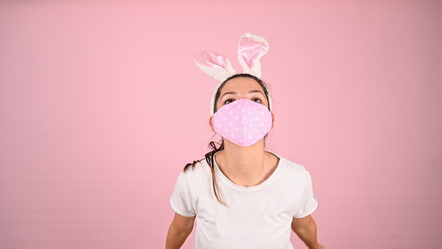 Girl in a mask with bunny ears, on a pink background. High quality photo