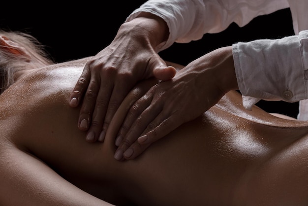 Girl massage therapist makes a massage closeup on a dark background closeup massage
