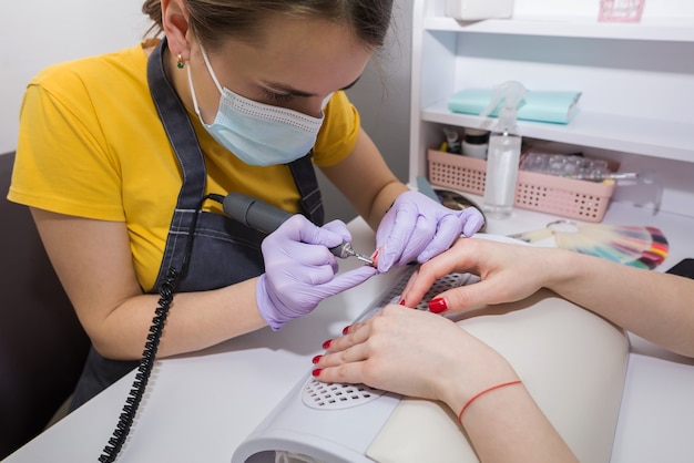 The girl the master makes a manicure for the client in the salon.