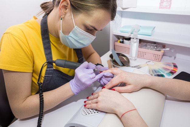 girl master makes a manicure in the salon. apparatus manicure. nail care concept.