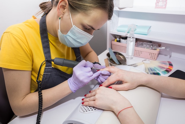 Girl master makes a manicure in the salon. Apparatus manicure. Nail care concept.