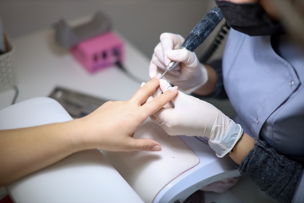 The girl master of nail service works with the client