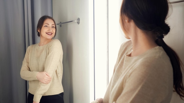 The girl measures the clothes in a fitting room.