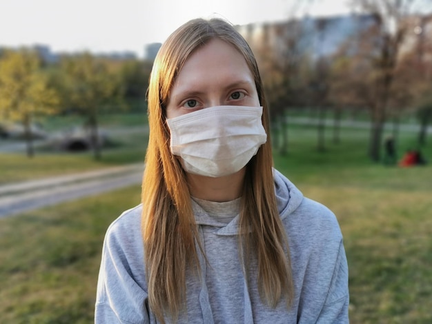 Девушка в медицинской маске крупным планом на весенней улице Защита от коронавируса 2020