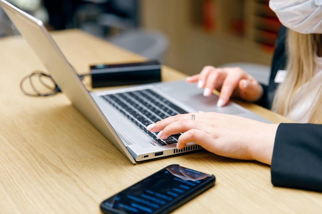 A girl in a medical mask is working on a laptop