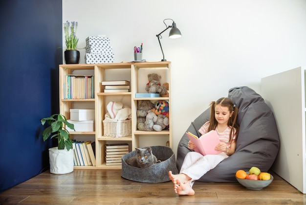 A girl in medical mask siting on wood floor and reading a books during quarantine