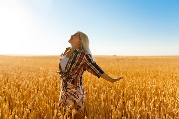 A girl in the midst of wheat spikelets. Caucasian woman posing with spikelets outside.