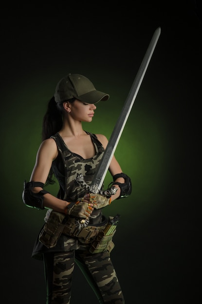 The girl in military special clothes posing with a gun in his hands on a dark background in the haze