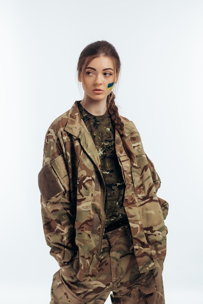 Ragazza in uniforme militare bandiera ucraina dell'ucraina sul volto guerra in ucraina bucha su sfondo bianco