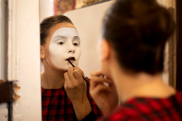 Girl mime in front of the mirror applies makeup