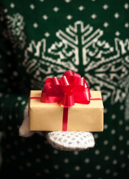 Девушка в варежках и свитер с зимним орнаментом держит рождественские подарки