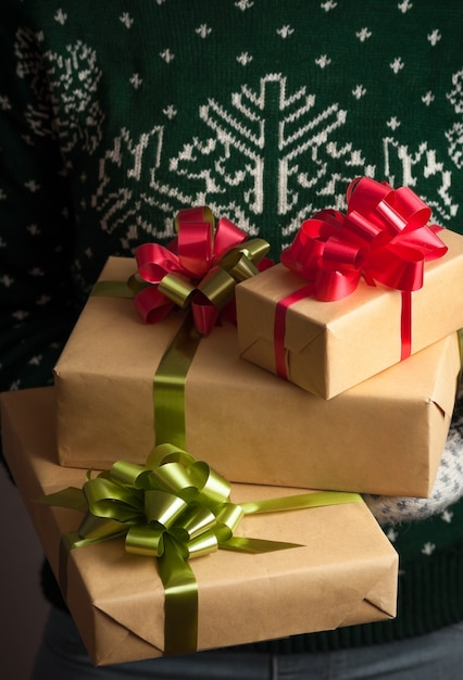 Girl in mittens and a sweater with a winter ornament holds Christmas gifts