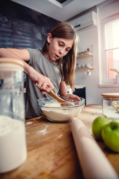 Girl mixing flour and sugar into bowl