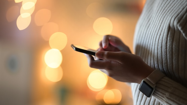 Ragazza e telefono cellulare durante la notte di bokeh