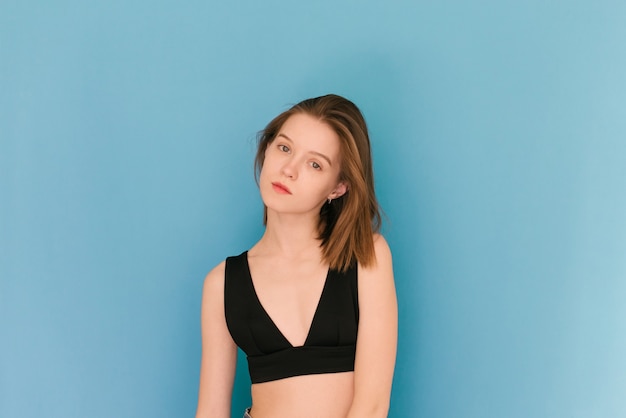 Girl of model appearance on a blue background in a bra