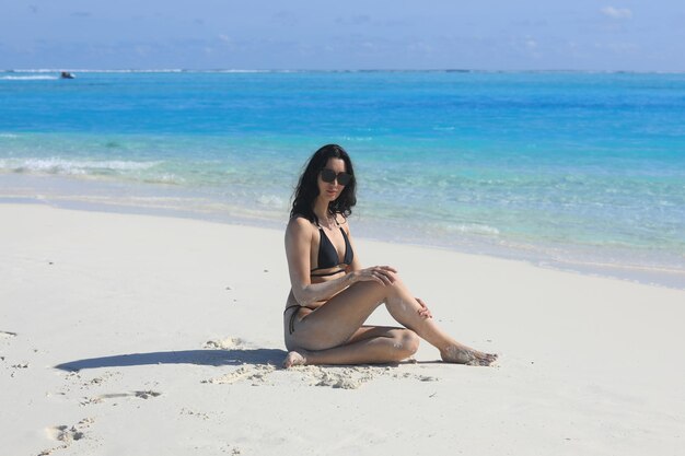 girl model in a black bikini on the white sand by the ocean